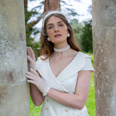 A bride wearing crochet white wedding gloves in the park
