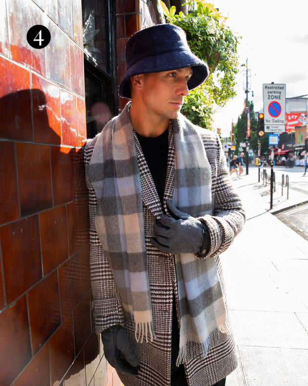 Man wearing check cashmere scarf in sky with bucket hat and gloves in the city