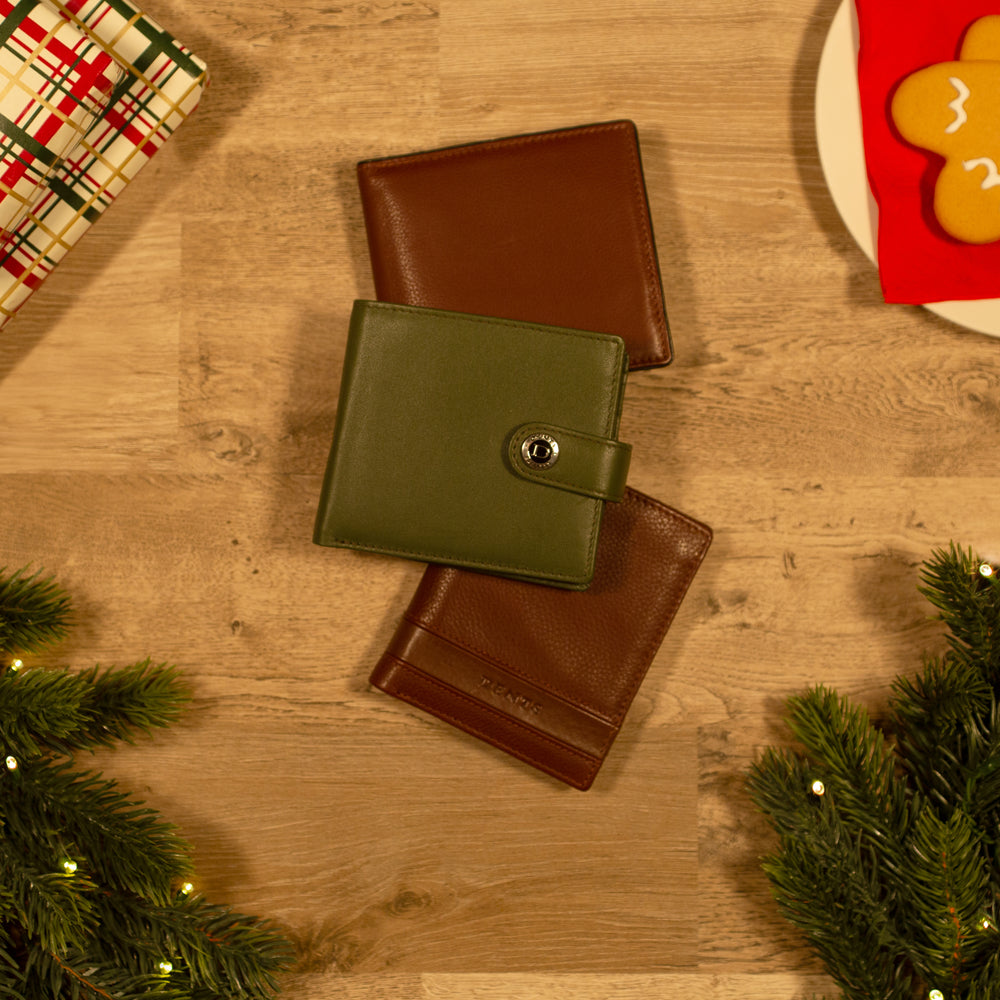 Selection of brown and green men's leather wallets against a wooden background with Christmas accessories