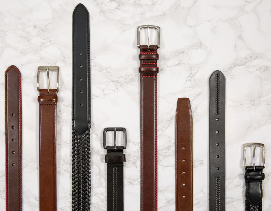 Men's leather belts in various colours and styles on a marble background