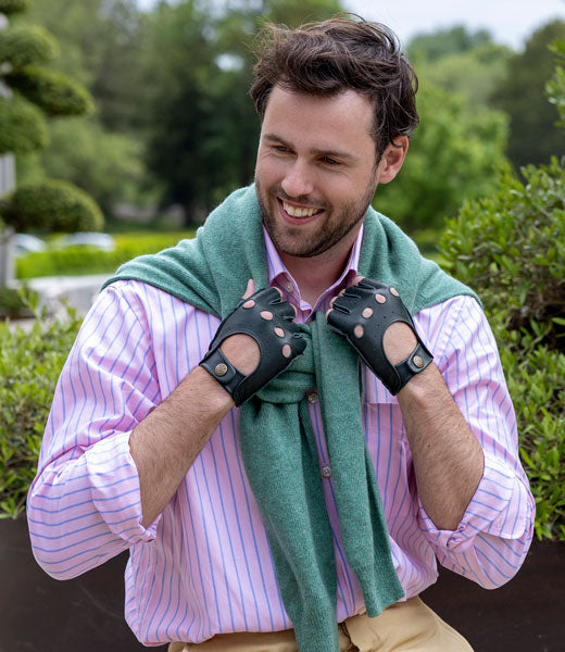 Man wearing fingerless leather driving gloves in green outdoors