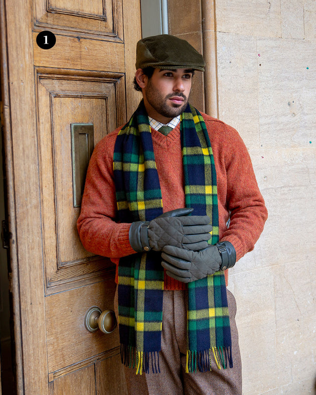 Man wearing touchscreen water-resistant lined leather gloves with waxed cotton quilting in olive by a grand door