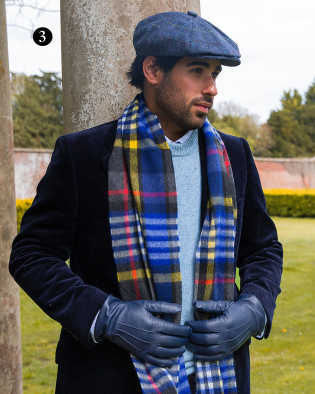 Man wearing heritage bold check cashmere scarf in night sky with leather navy gloves and navy tweed hat