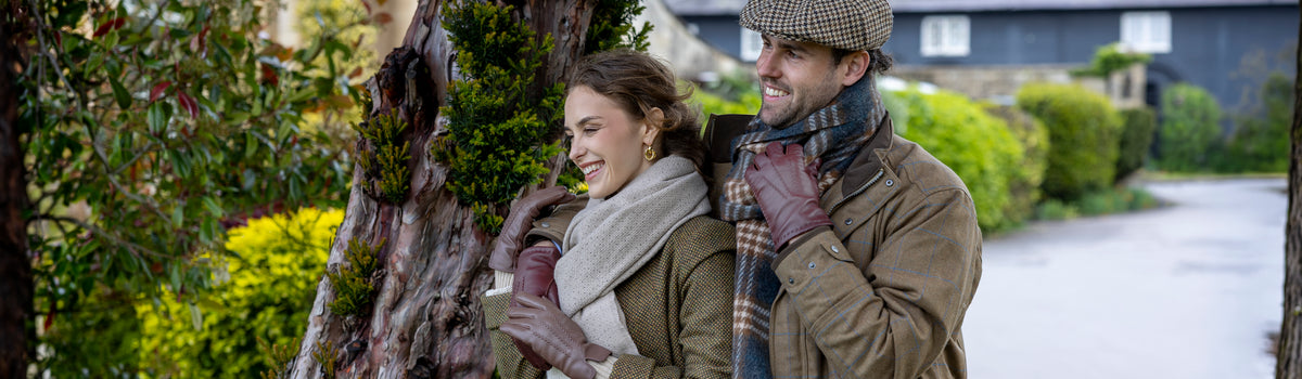 Man and woman wearing leather gloves, scarves and hat outdoors