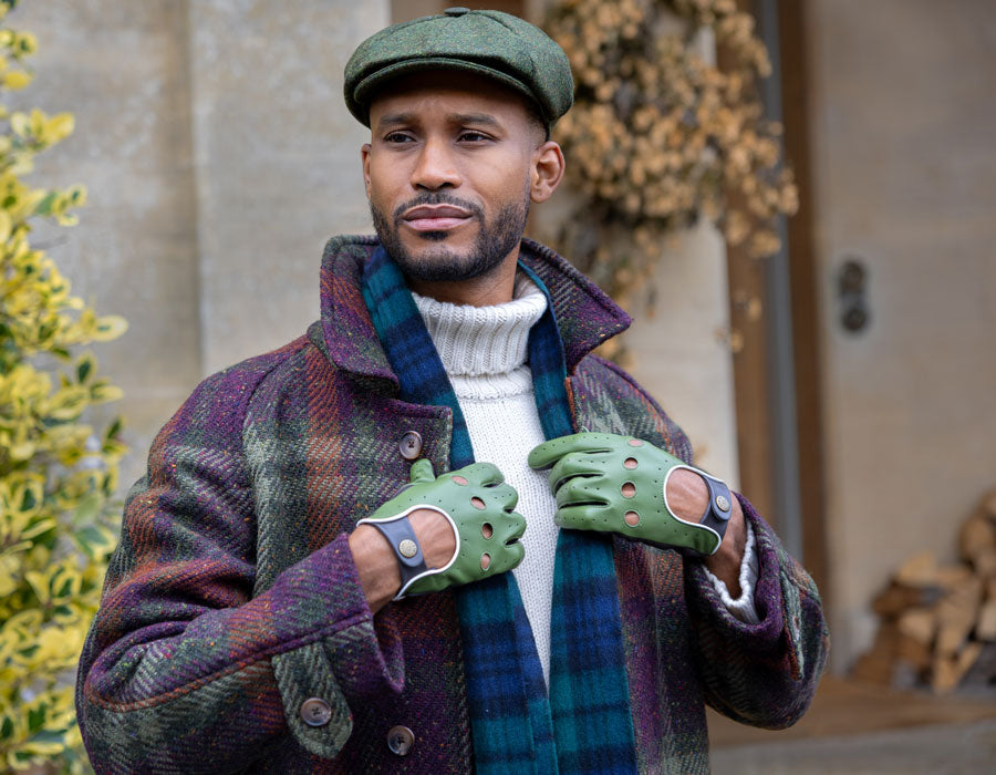 Man wearing green leather touchscreen driving gloves with hat outdoors