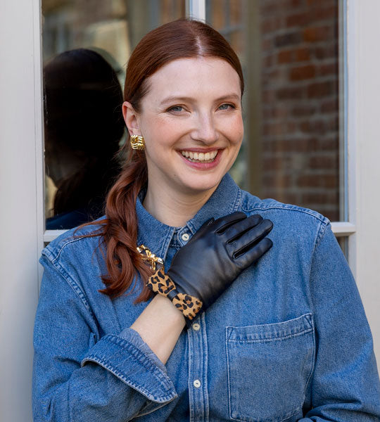 Woman wearing black leather gloves with an animal print bow 