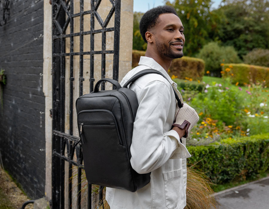 Man wearing black leather backpack with driving gloves in natural, outside in the garden.