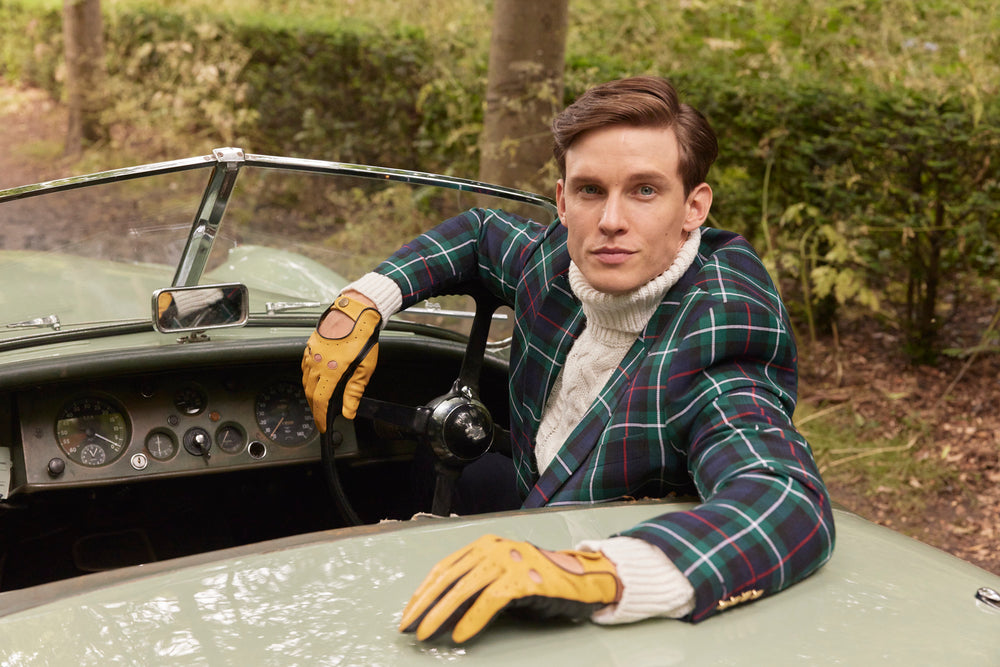 Man wearing yellow leather touchscreen driving gloves, sitting in a car. 