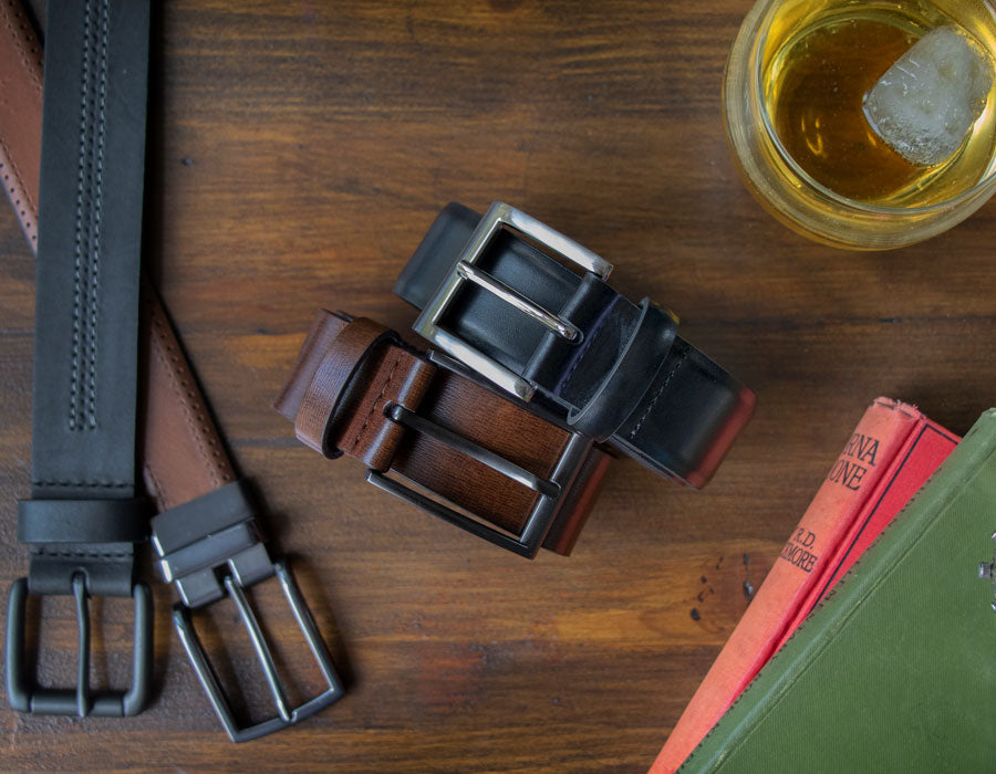 men's leather belts in various colours and styles laid out of a wooden table