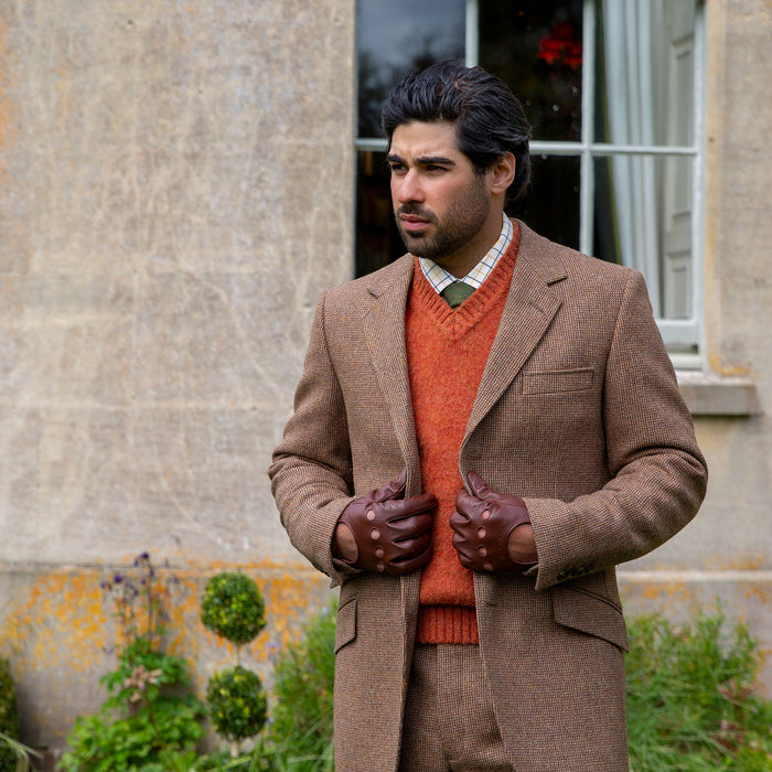Man wearing leather driving gloves in english tan with a tweed jacket