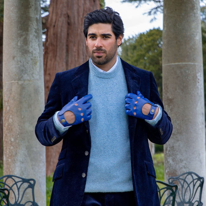 Man wearing leather driving gloves in royal blue with a velvet jacket