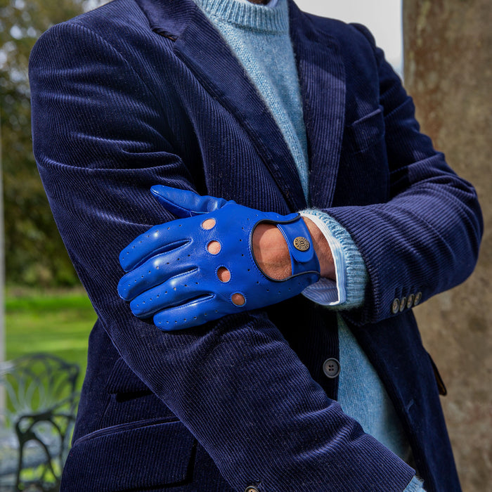 Man wearing leather driving gloves in royal blue with a velvet jacket