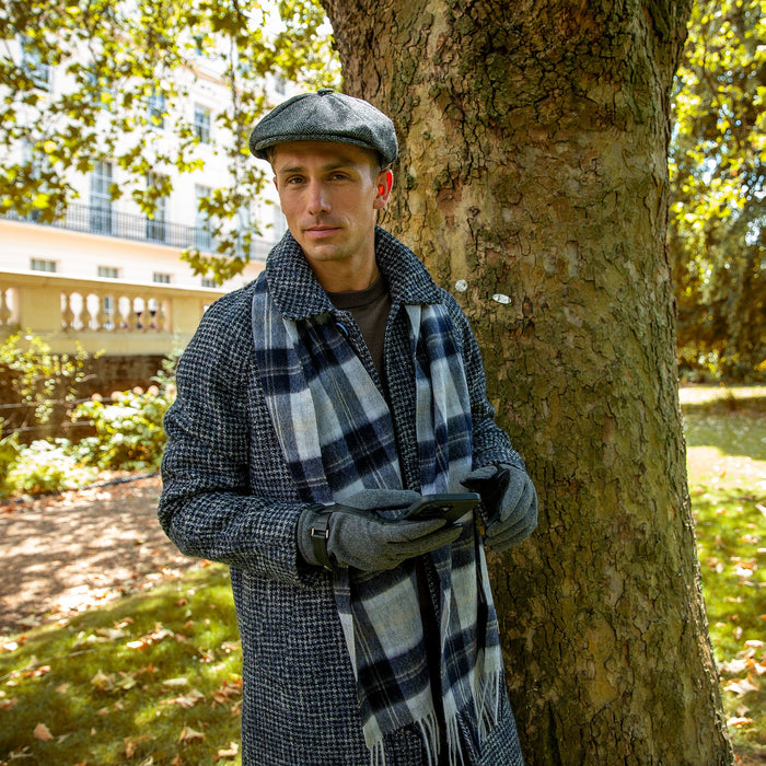 Man wearing touchscreen flannel and leather gloves in charcoal with a silver check scarf and tweed hat at the park