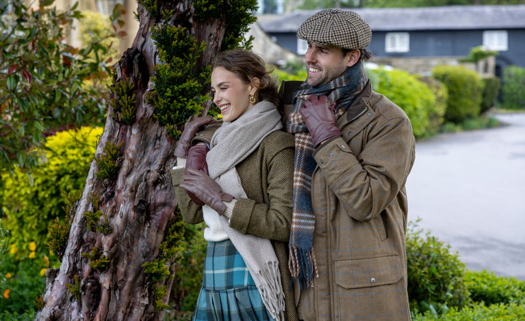Man and woman wearing leather gloves, scarves and hat outdoors