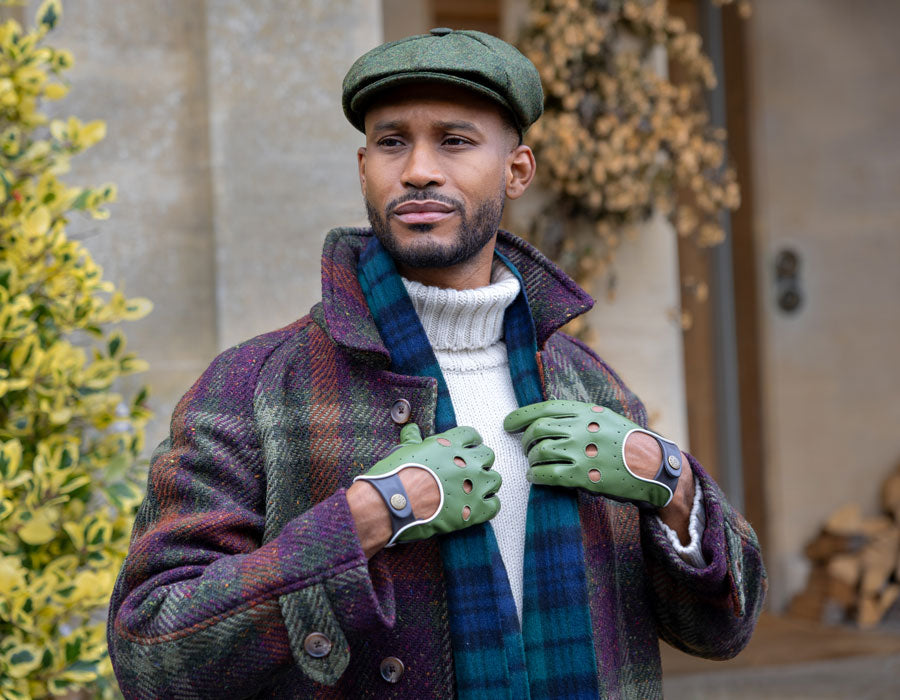 Man wearing leather driving gloves in green with a tweed hat and cashmere scarf outdoors