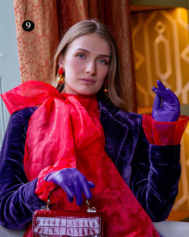 Woman wearing three point lined leather gloves in amethyst in a grand room