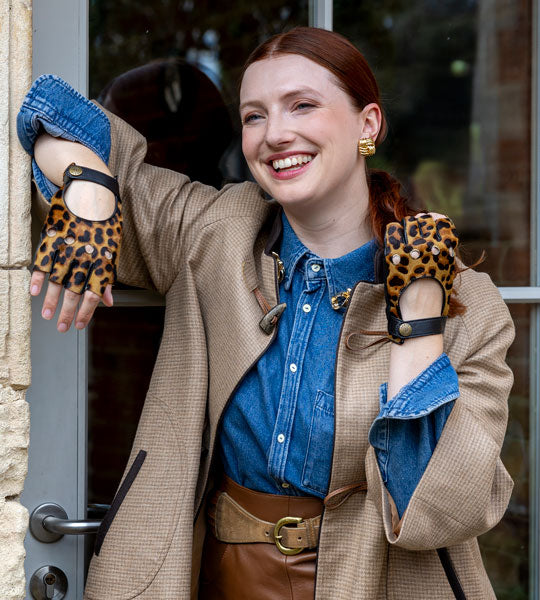 Woman wearing animal print fingerless leather gloves in doorway.