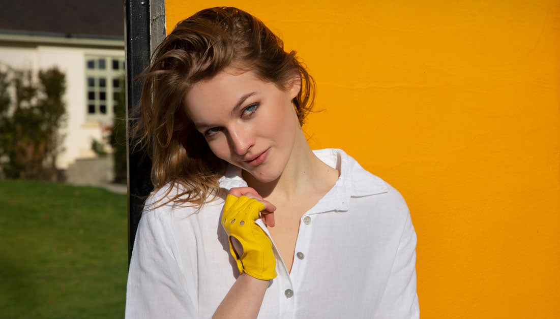 Woman wearing fingerless leather driving gloves in yellow outdoors