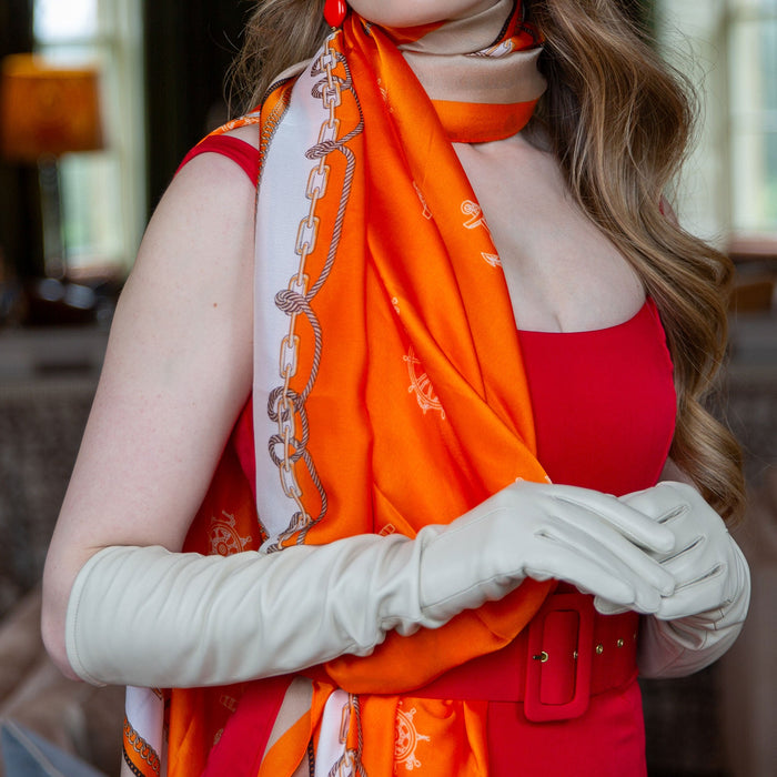 Woman wearing nautical print silk-like lightweight scarf in orange with long leather ivory gloves