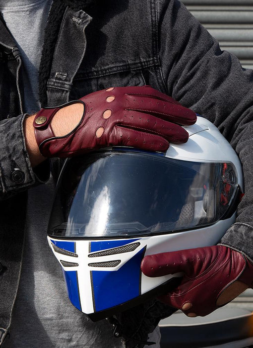 Man wearing wine and black leather driving gloves carrying a motorcycle helmet