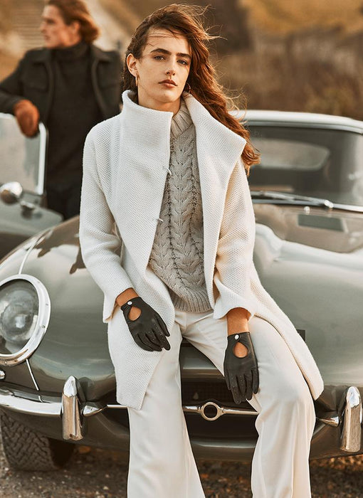 woman wearing a white suit with black leather gloves